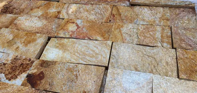 Close-up of cut rock-face gneiss cladding tiles in warm rusty tones