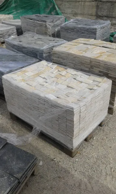 Wrapped pallets of cream and grey cut gneiss cladding stones in the storage yard